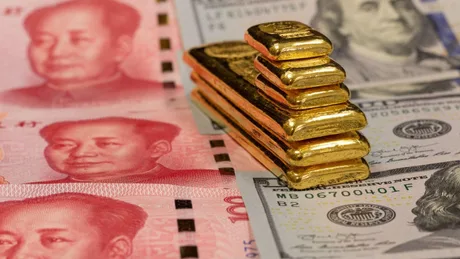 Aur și bancnote chinezești pe un fundal de dolari americani.