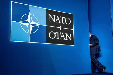 Logo-ul NATO pe un fundal albastru, simbolizând alianța militară.