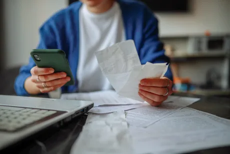 Utilizator verificând bonuri fiscale pe telefonul mobil.