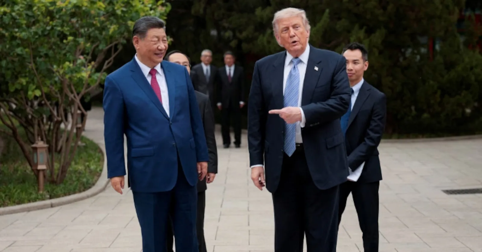 Trump și Xi discutând la summit, cu un peisaj verde în fundal.