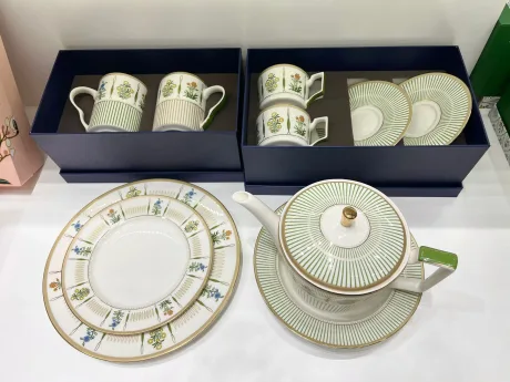 Set de ceramică cu farfurii, cești și ceainic, design elegant și detalii florale.