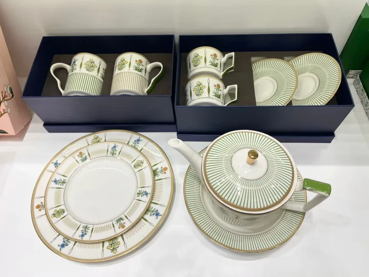 Set de ceramică cu farfurii, cești și ceainic, design elegant și detalii florale.
