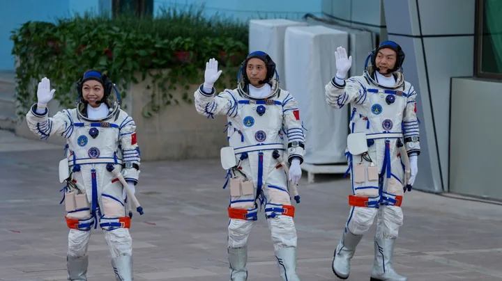 Trei astronauți salută înainte de lansarea misiunii Shenzhou-23 către stația Tiangong.