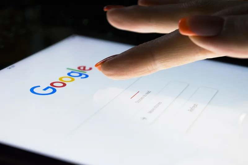 Ecran de căutare Google cu o mână care atinge display-ul
