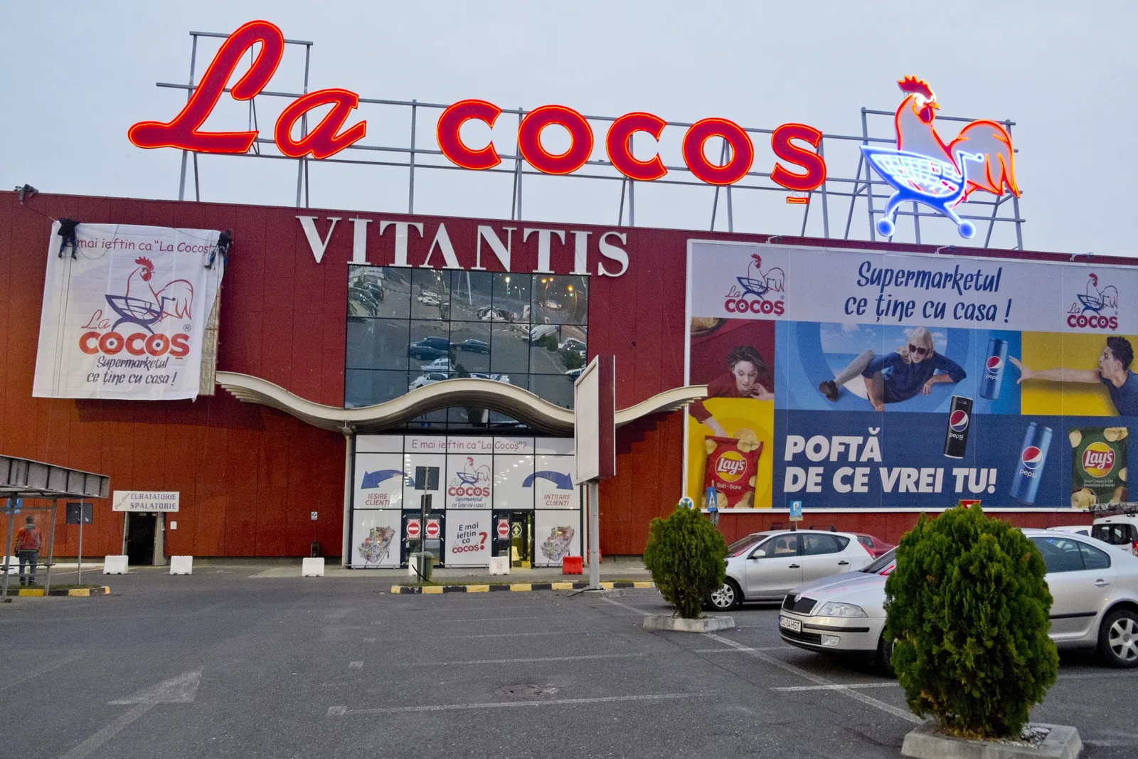 Magazin La Cocoș cu panouri publicitare și logo vizibil.