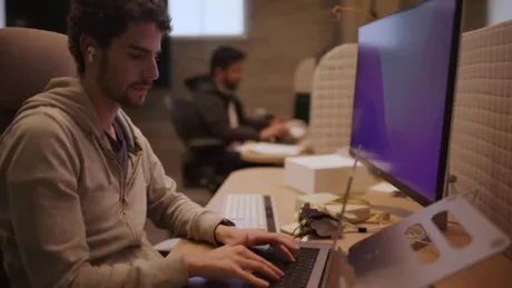 Persoane lucrând la birou, interacționând cu tehnologia modernă.