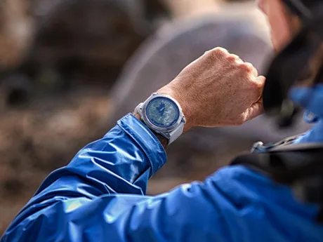 Ceas inteligent Garmin purtat pe mână, în natură, cu un design modern.