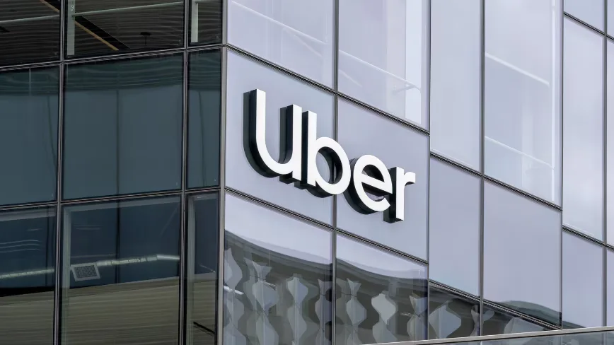 Logo-ul Uber pe o clădire modernă, reflectând cerul.