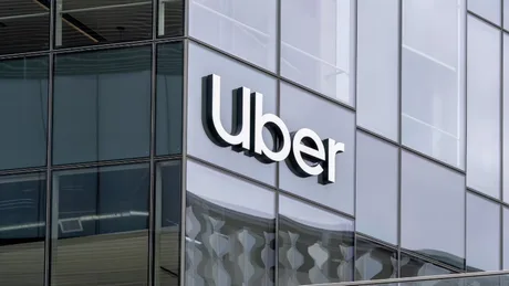 Logo-ul Uber pe o clădire modernă, reflectând cerul.