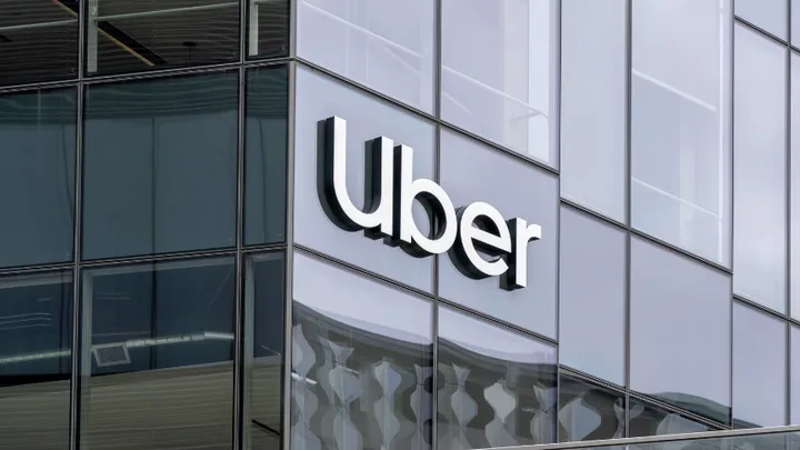 Logo-ul Uber pe o clădire modernă, reflectând cerul.