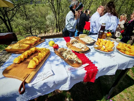 Produse tradiționale din Banat expuse pe o masă în natură.