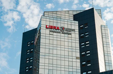 Clădire modernă a Libra Internet Bank, cu feronerie din sticlă și cer senin.