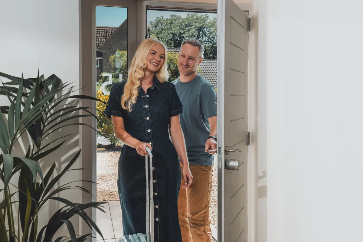 Cuplu fericit intrând în casă cu bagaje.