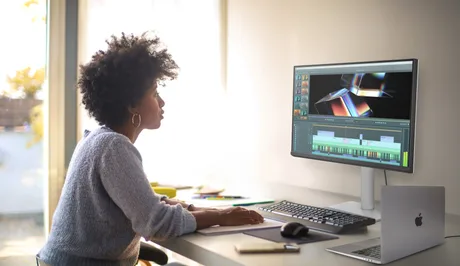 Utilizator lucrând la un monitor BenQ, concentrat pe editare video.