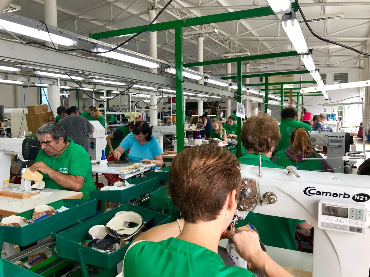 Angajați lucrând în fabrica de încălțăminte din România