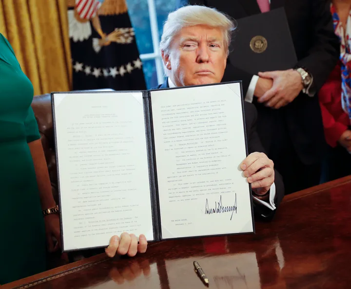 Donald Trump ținând un document important în biroul său.