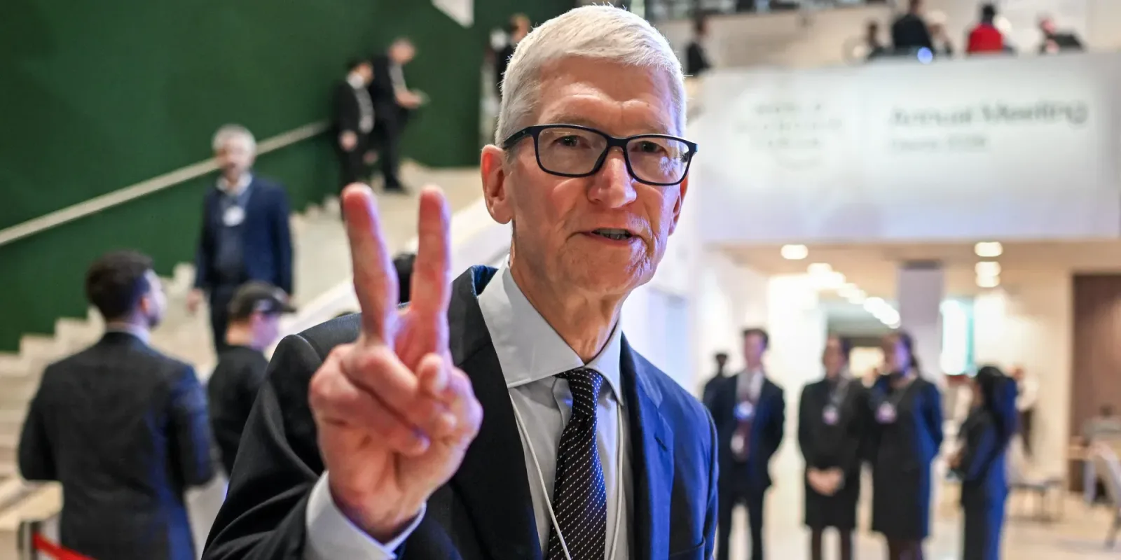 Tim Cook zâmbind și făcând semnul victoriei la o întâlnire.