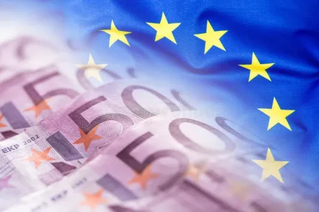 Bancnote euro și steagul Uniunii Europene în fundal.