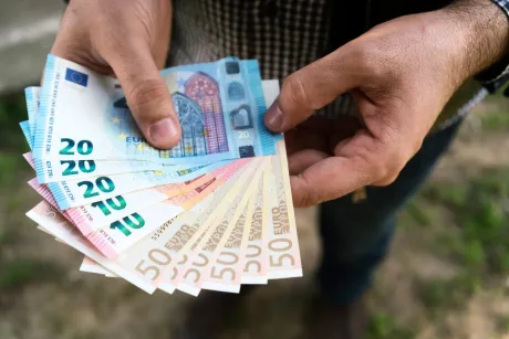 Bărbat ținând bancnote de euro în mână, pregătit pentru plăți.