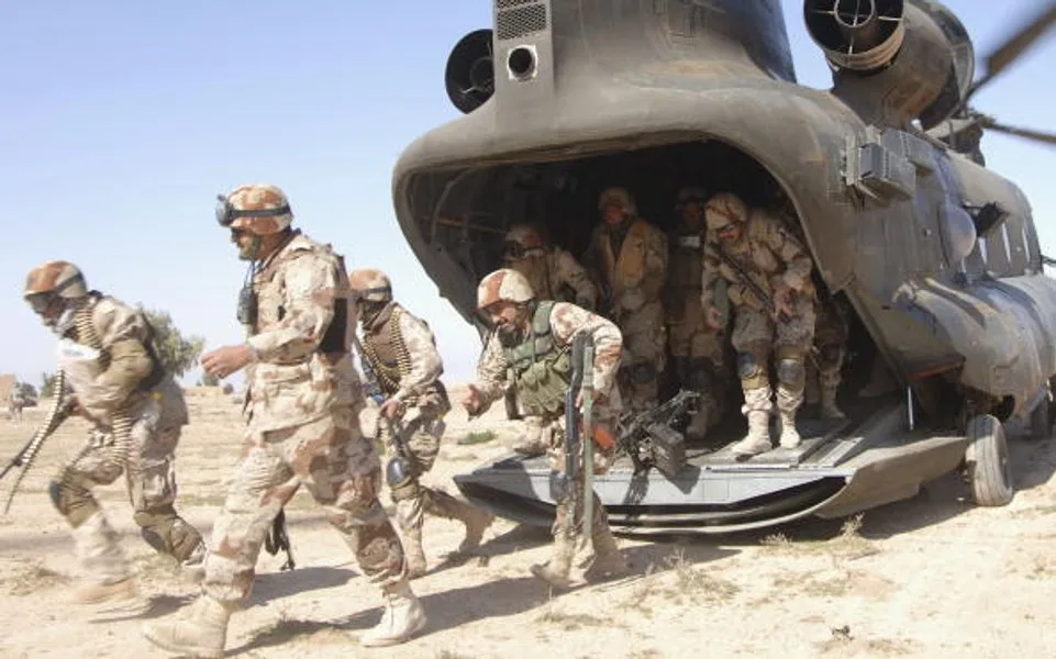 Soldați americani desfășurându-se dintr-un elicopter în teren arid.