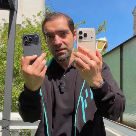 Un bărbat ținând în mâini două telefoane Honor 600 Pro, pe fundal verde.