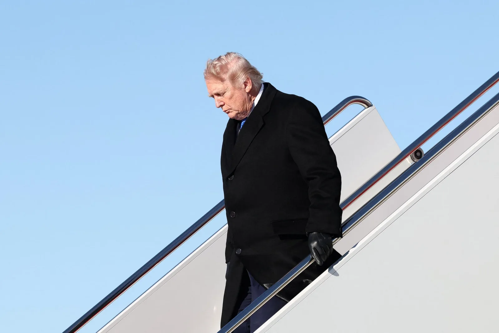 Donald Trump coborând dintr-un avion, într-o zi senină.