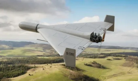 Dronă de tip Geran-2 zburând deasupra unui peisaj verde, cu aripi mari și motor vizibil.