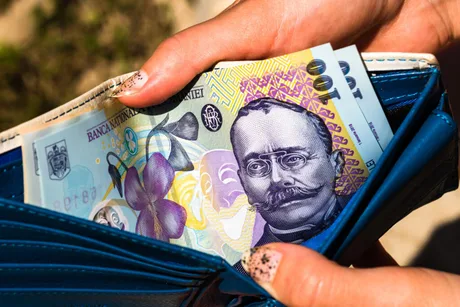 Bancnote românești scoase dintr-un portofel albastru.