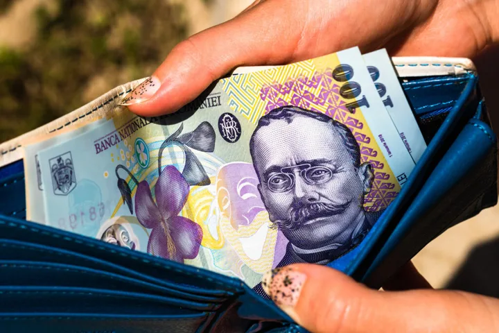 Bancnote românești scoase dintr-un portofel albastru.