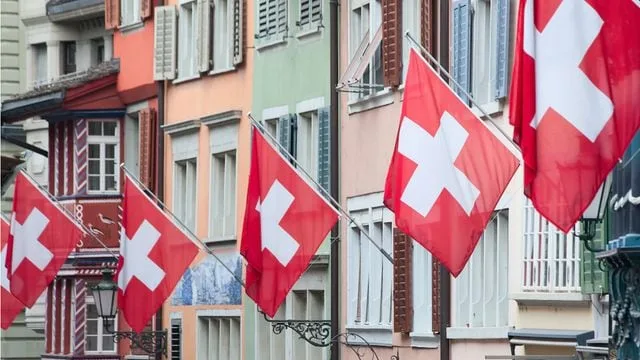 Steaguri elvețiene fluturând pe clădiri colorate dintr-un oraș elvețian.