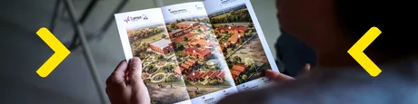 Persoană examinând un pliant despre proiecte de sprijin pentru comunitate.