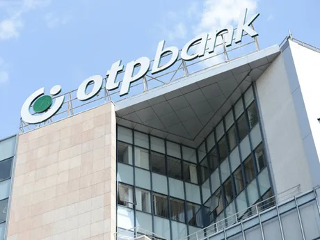 Clădirea OTP Bank cu logo-ul băncii pe fațadă, sub un cer senin.