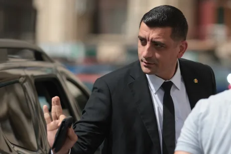 Un bărbat îmbrăcat elegant, gesticulând într-un mediu urban aglomerat.