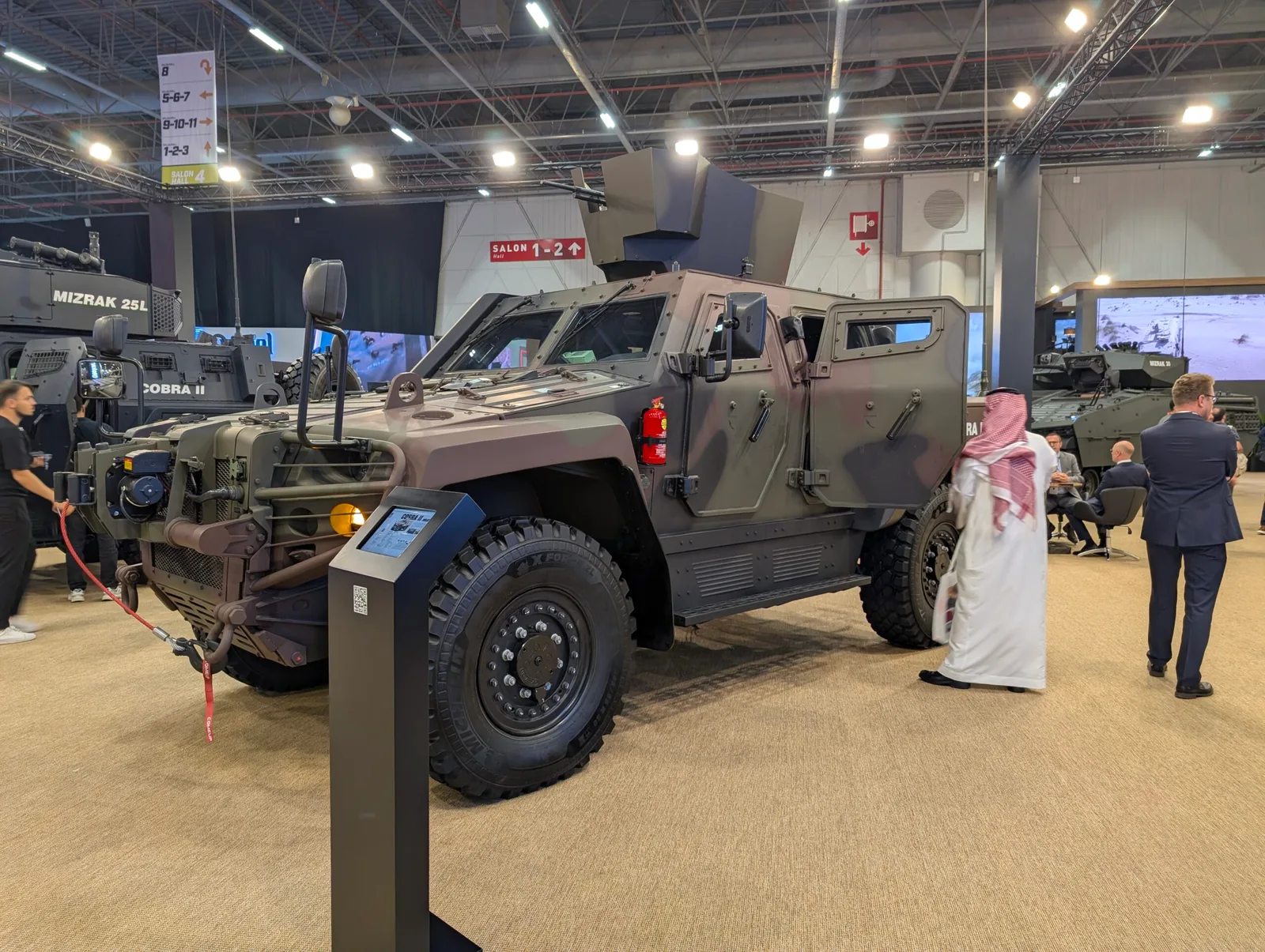 Vehicul militar modern expus la un târg de apărare, cu detalii tehnice vizibile.