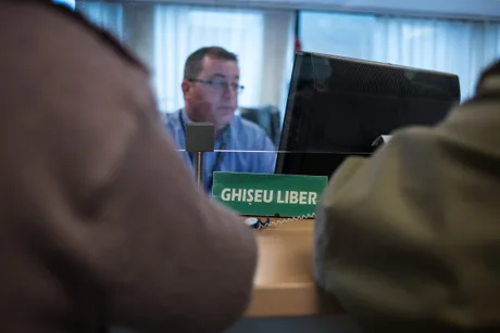 Persoane discutând despre impozitul pe venit la ghișeu.