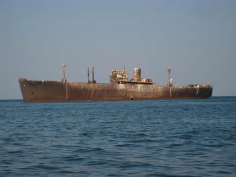 O navă veche ancorată în largul mării, cu un aspect deteriorat.