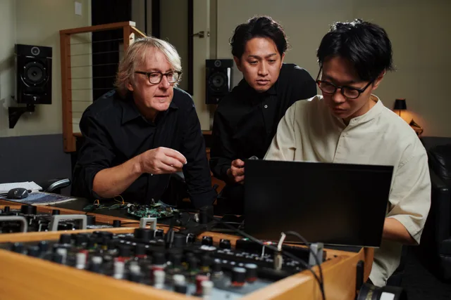 Ingineri audio discutând despre procesarea sunetului.