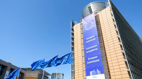 Clădirea Comisiei Europene cu steaguri ale Uniunii Europene în față.