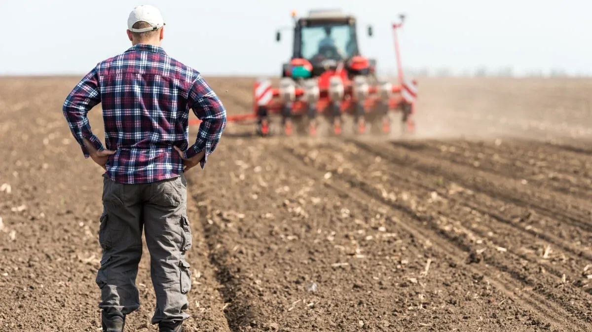 Fermier român observând lucrările agricole pe un câmp arat.
