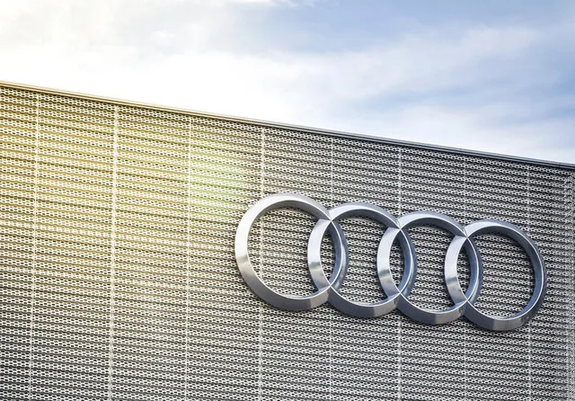 Logo-ul Audi pe un perete modern, simbolizând inovația în industria auto.