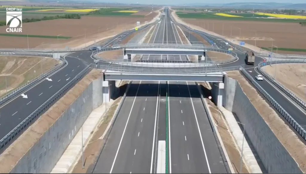 Vedere a unei autostrăzi moderne, cu peisaj rural în fundal.