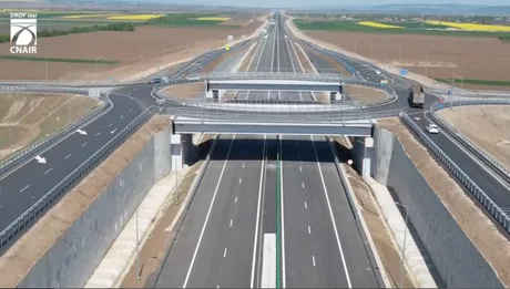 Vedere a unei autostrăzi moderne, cu peisaj rural în fundal.