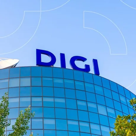 Clădire modernă cu logo-ul DIGI pe fațadă, sub un cer senin.