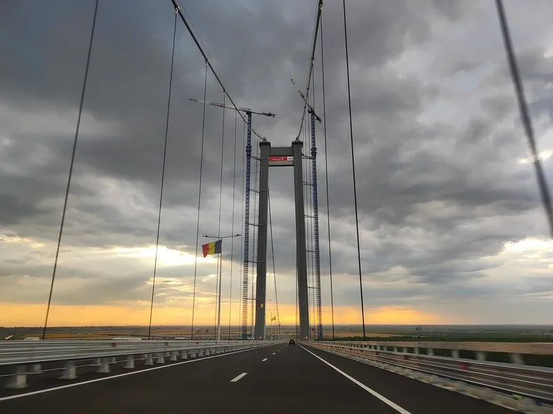 Podul Brăila în condiții meteo variate, cu nori și lumini de apus.