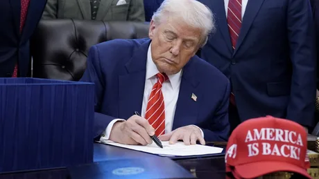 Donald Trump semnează un document important la birou.