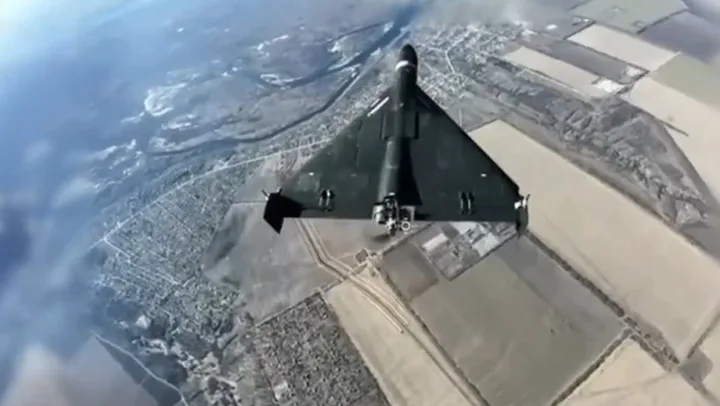 Dronă de tip Shahed zburând deasupra unui peisaj rural vast.