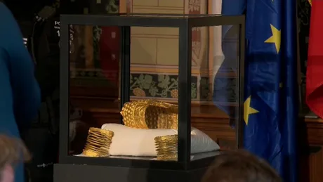 Tezaurul românesc expus într-un cazan de sticlă, evidențiind aurul recuperat.