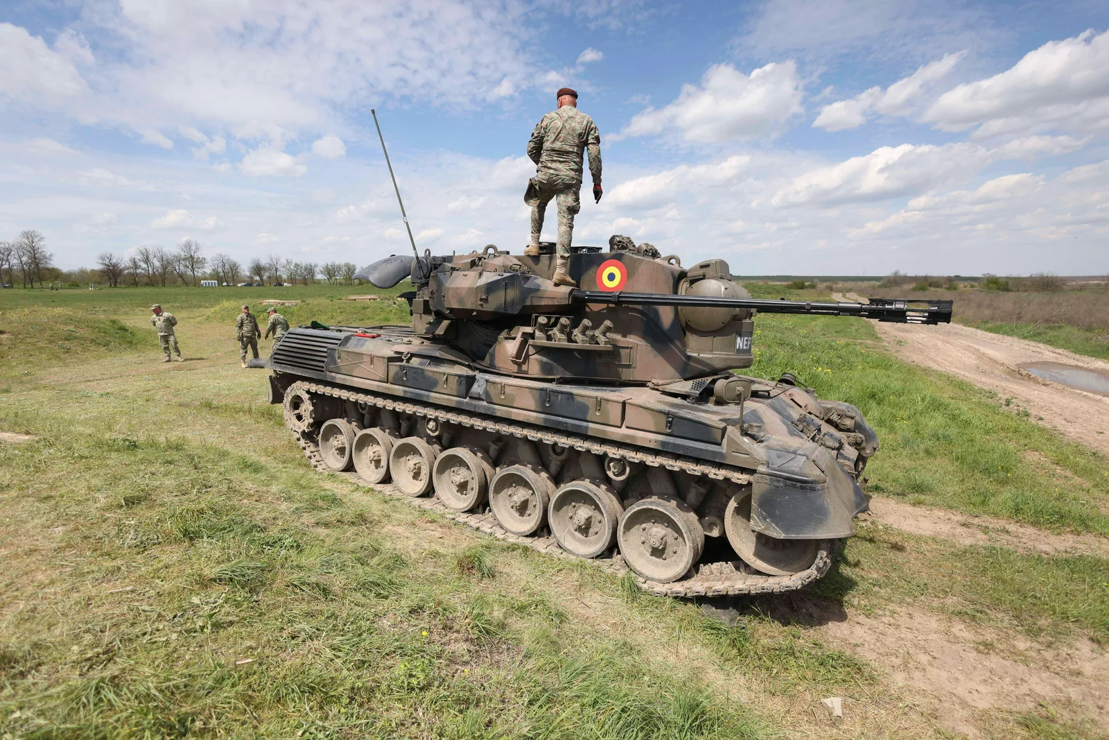 Tanc militar pe câmp, soldat în poziție de observație.
