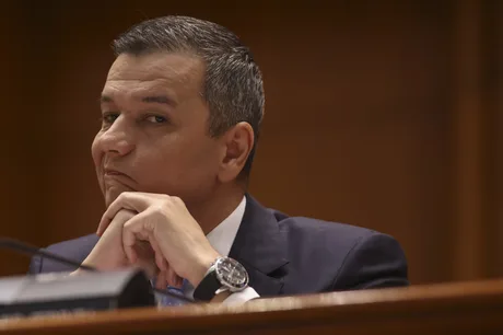 Un politician în timpul unei ședințe, cu o expresie gânditoare.