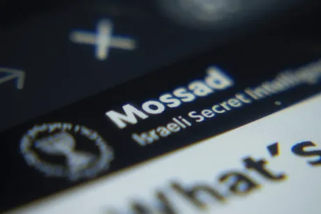 Logo-ul Mossad, agenția de informații israeliană, pe un fundal întunecat.